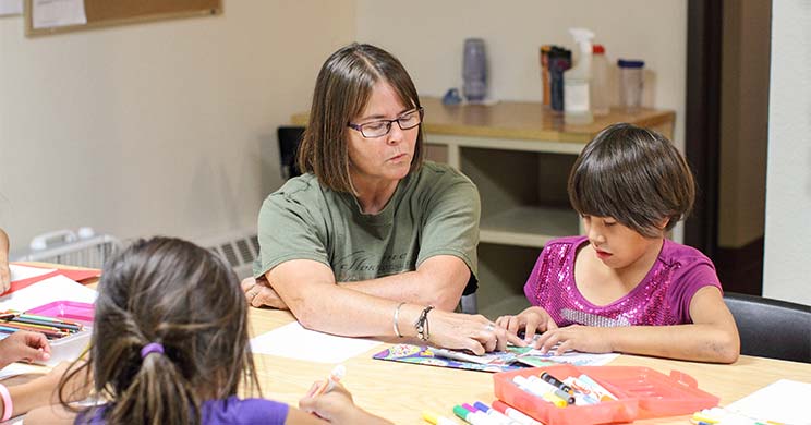 Kelly and Erin work on their homework with their houseparent.