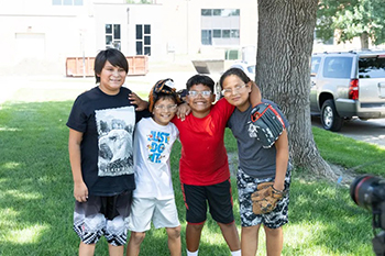 Four boys reunite after a summer apart, sharing big smiles as they pose together for a photo.