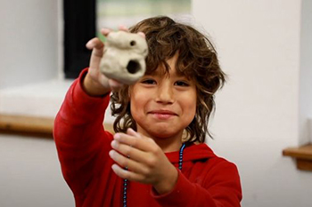 A St. Joseph’s Indian School student proudly holds up their in-progress jack-o’-lantern sculpture.