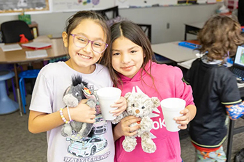 With their favorite stuffed animals in hand and cocoa to keep them warm, two girls enjoy the cozy comfort of Snugs & Hugs Day.