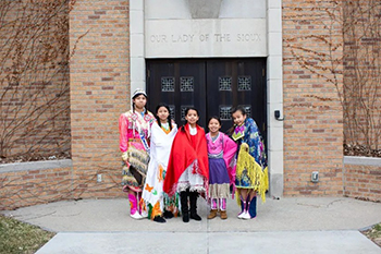 Student dancers, dressed in colorful regalia, welcome and greet the congregation before gracefully leading the procession down the aisle at Lakota Mass.