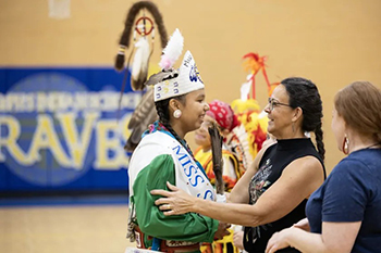 LaRayne, (center), St. Joseph’s Indian School’s Native American Studies Lead, smiles at a previous Miss St. Joseph’s winner.