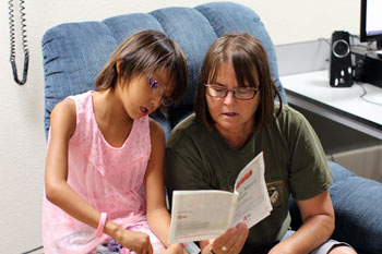 St. Joseph's Indian School staff reading a book to a Lakota girl