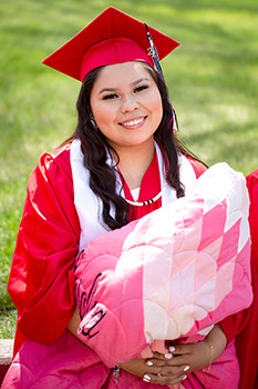 Graduating Native American women holding a beautiful star quilt.